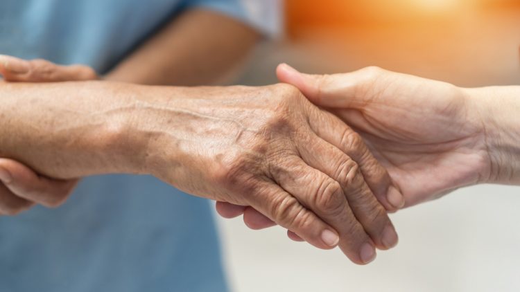 Hand of Alzheimer's patient holding nurse's hand