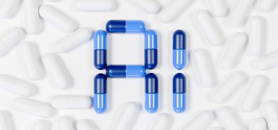 A collection of white capsules scattered on a white surface, with blue and dark blue capsules arranged in the center to form the letters 'A' and 'I'