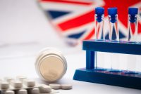 Laboratory test tubes and medicines in front of a UK flag, representing UK regulation of biomedical research and testing.