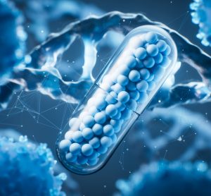 3D illustration of a pharmaceutical capsule filled with small blue spheres, surrounded by abstract biological cells and molecular structures, symbolizing drug discovery and biotechnology.