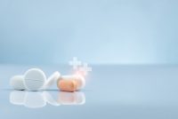 Close-up of white and orange tablets with glowing medical cross icons symbolising advanced therapies and innovative drug development.