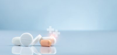 Close-up of white and orange tablets with glowing medical cross icons symbolising advanced therapies and innovative drug development.