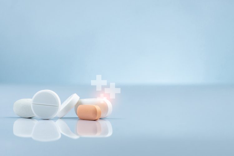 Close-up of white and orange tablets with glowing medical cross icons symbolising advanced therapies and innovative drug development.