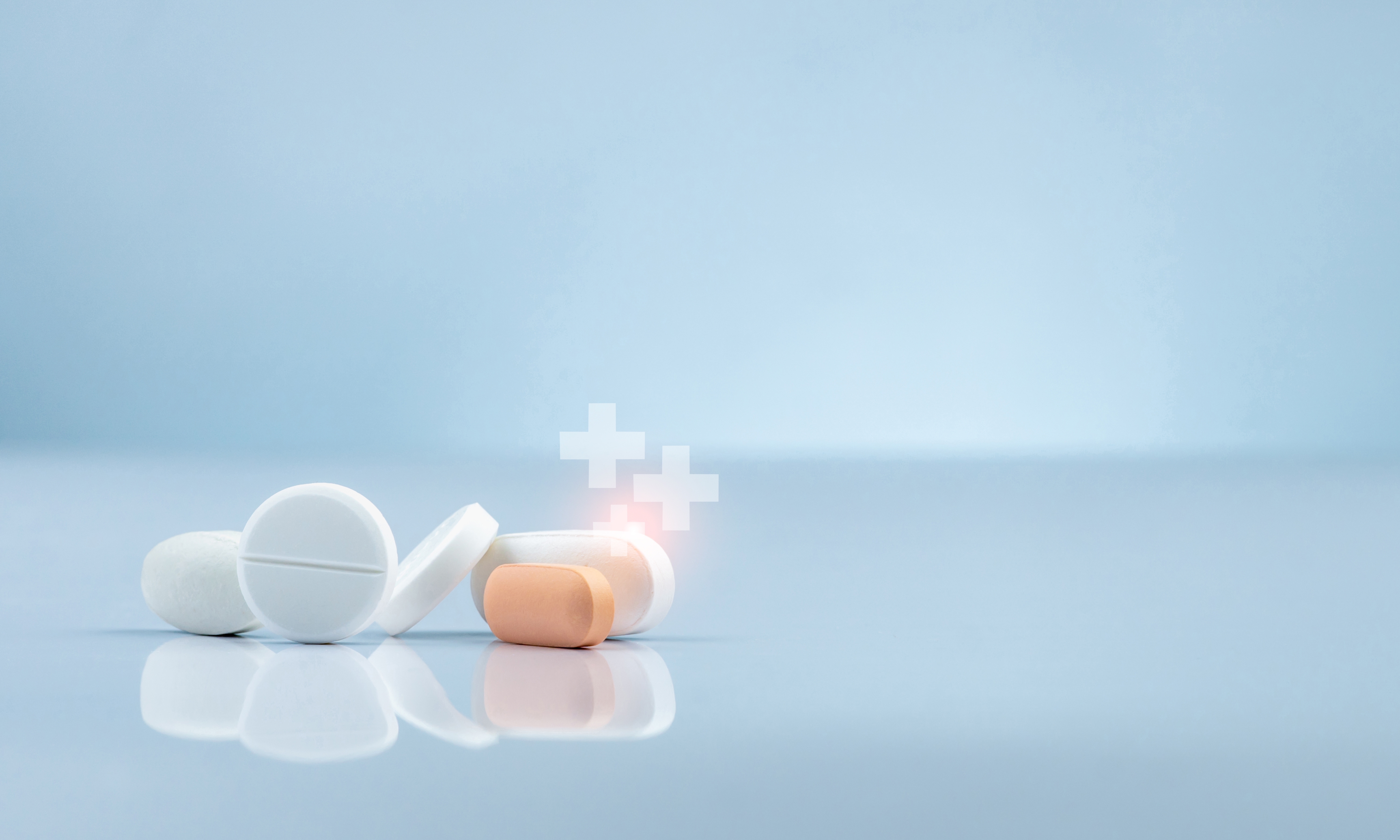 Close-up of white and orange tablets with glowing medical cross icons symbolising advanced therapies and innovative drug development.