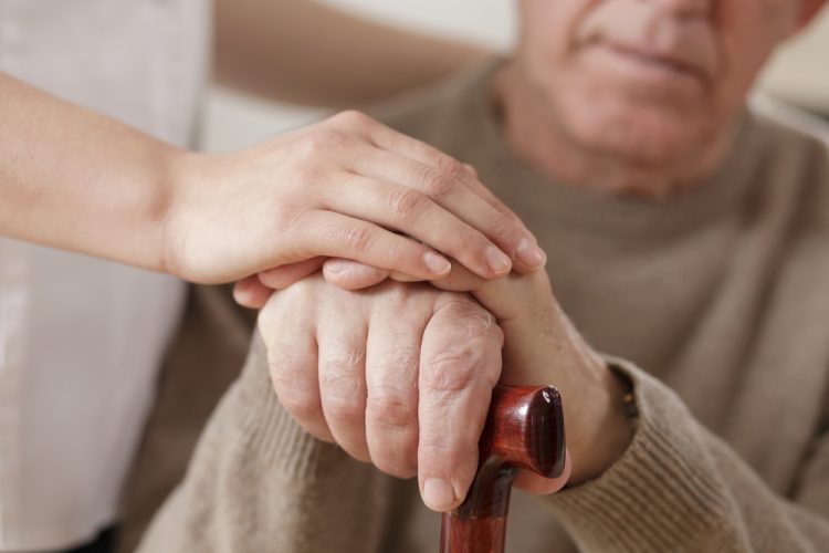 Care worker holding hand of Parkinson's patient