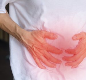 Man with inflammatory bowel system holding his stomach highlighted in red
