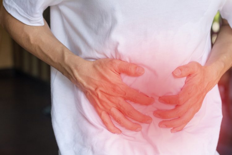 Man with inflammatory bowel system holding his stomach highlighted in red