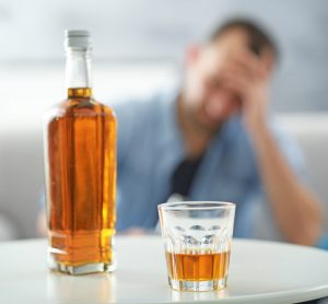 Man with bottle of whiskey on table