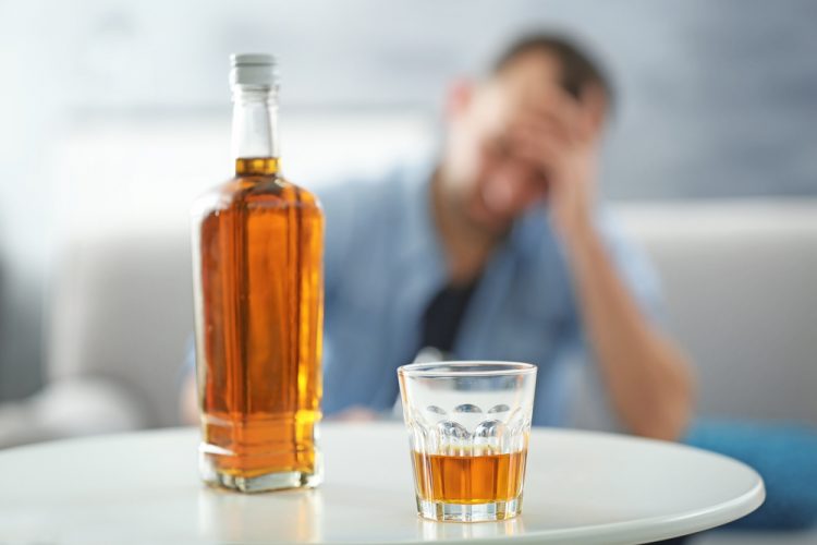 Man with bottle of whiskey on table