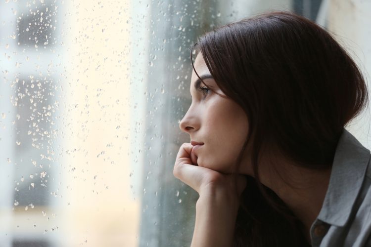 Woman with depression looking out of window