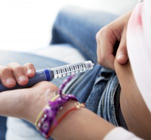 diabetic person using pre-filled syringe to inject their stomach with insulin