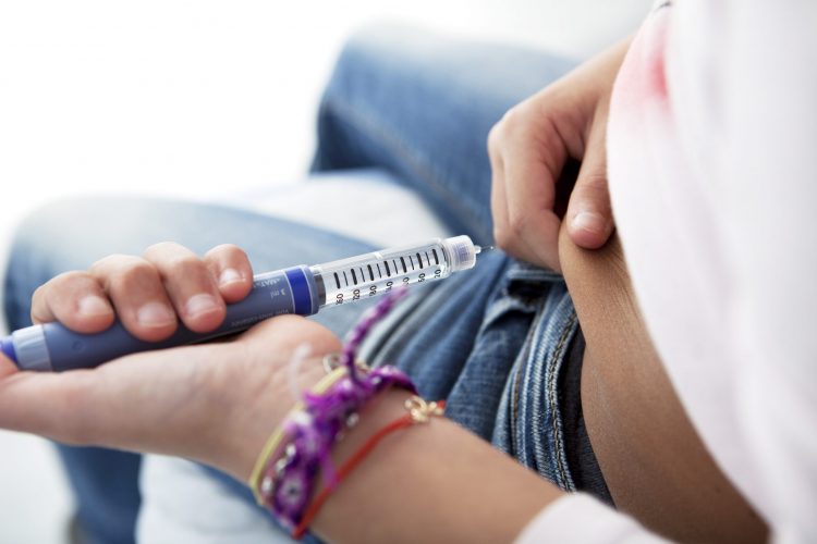 diabetic person using pre-filled syringe to inject their stomach with insulin