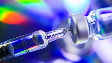 close up photo of a syringe drawing liquid from a medicine vial