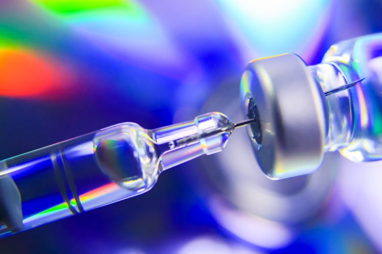 close up photo of a syringe drawing liquid from a medicine vial